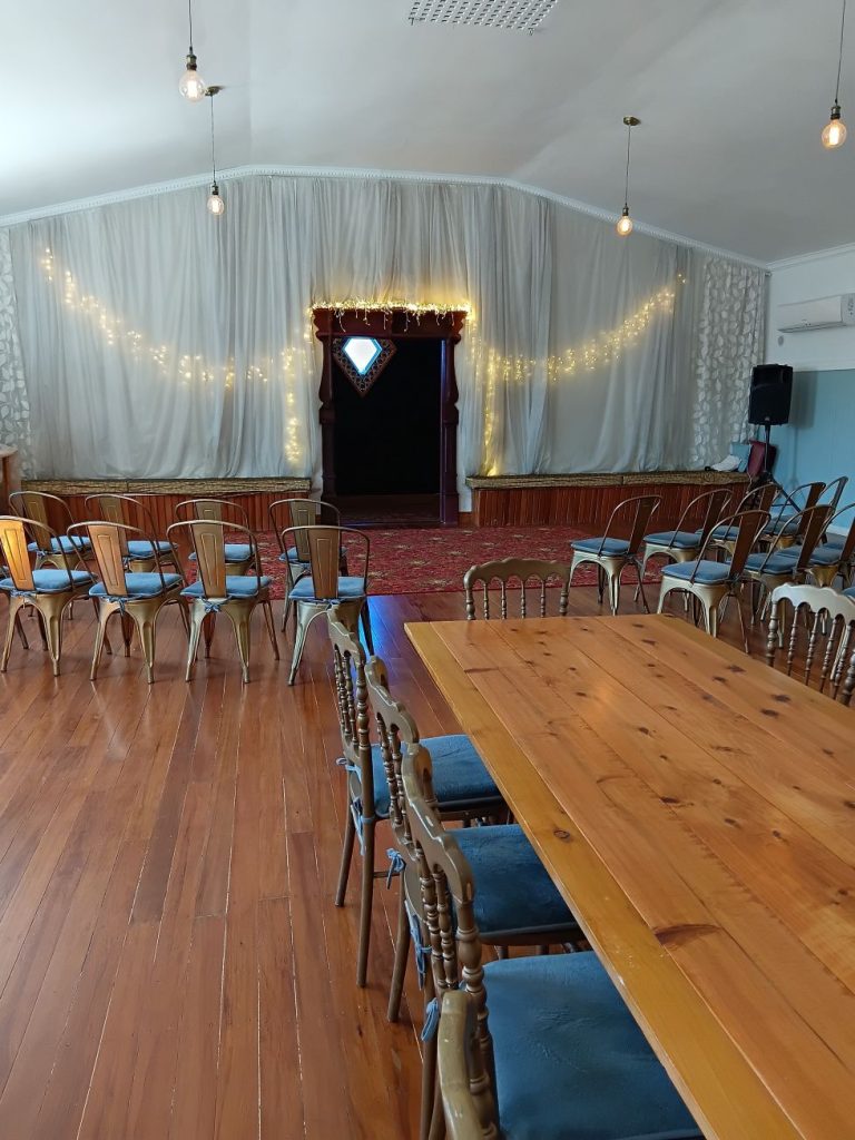A tables and rows of chairs facing the hall entrance.