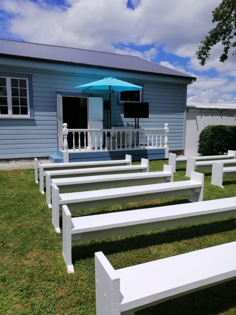 Rows of pews lines up in front of the hall side entrance door with an umbrella on the raised porch.