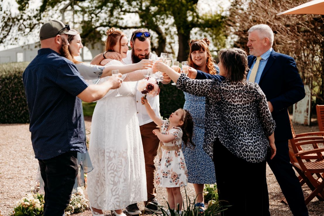 A small group celebrate with a glass of bubbles in the courtyard.