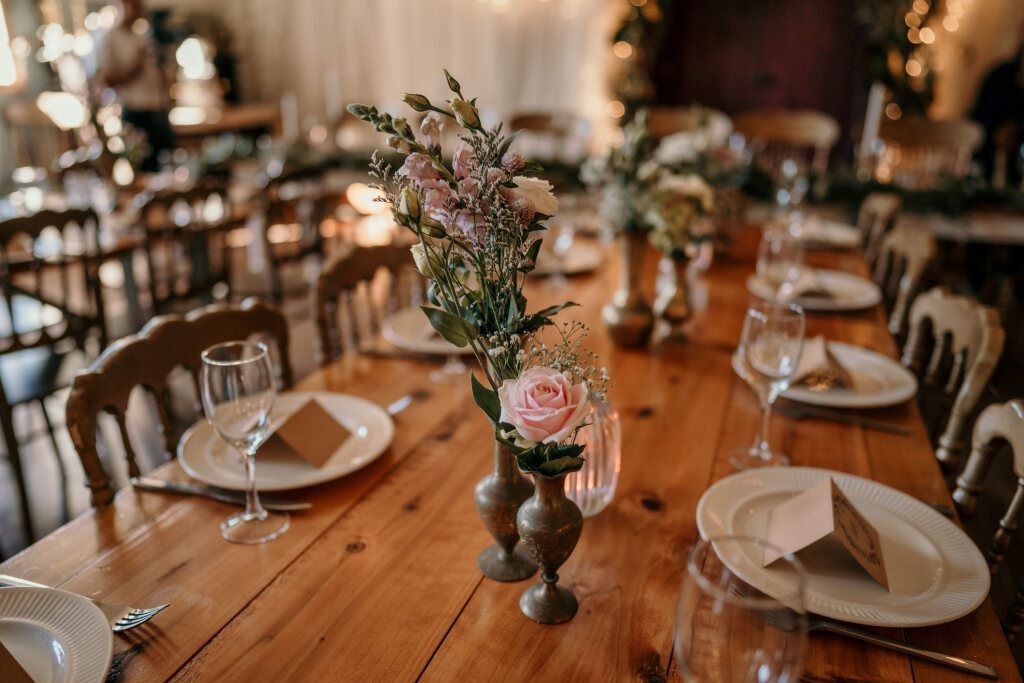 Vintage style table decor decorating a wedding reception table with pink flowers and brass vases.